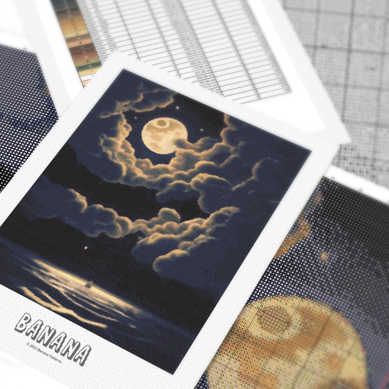 Peut inclure: Un motif de point de croix repr&eacute;sentant une sc&egrave;ne de nuit avec une pleine lune, des nuages et de l'eau. Le mot "BANANA" est imprim&eacute; en bas. D'autres motifs et graphiques de point de croix sont visibles en arri&egrave;re-plan.
