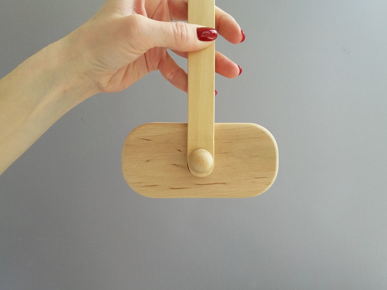 K&ouml;nnte beinhalten: Ein ovales Objekt aus Holz mit einem Holzgriff. Das Objekt h&auml;ngt am Griff und wird von einer Hand gehalten.