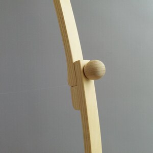 K&ouml;nnte beinhalten: Nahaufnahme eines Holzrahmens mit einem runden Knopf. Der Rahmen ist aus hellem Holz gefertigt und hat eine glatte Oberfl&auml;che.