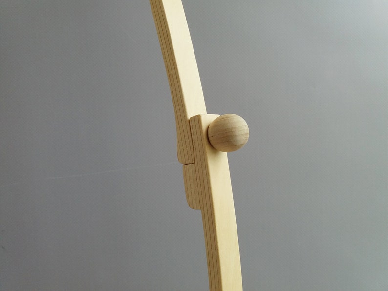 K&ouml;nnte beinhalten: Nahaufnahme eines Holzrahmens mit einem runden Knopf. Der Rahmen ist aus hellem Holz gefertigt und hat eine glatte Oberfl&auml;che.