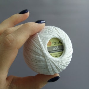 May include: White ball of yarn labelled "YarnArt IRIS" with the website www.yarnart.info and 100% Cotton Mercerized, Net 20 g/ 705 yds.