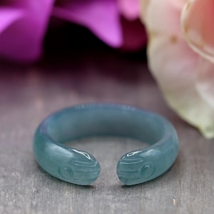 Könnte beinhalten: Ein hellblauer Ring mit einem geschnitzten Design aus zwei Händen, die sich halten. Der Ring ist aus Jade und ein einzigartiges Schmuckstück.