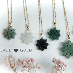 May include: Six gold chain necklaces with jade flower pendants. The flowers are carved in a snowflake design and come in shades of green, white, and black.