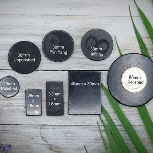 May include: Assortment of black slate coasters in various sizes and shapes. The coasters are unpolished, polished, and feature designs like Yin Yang and infinity symbols. The text on the coasters includes measurements in millimeters.