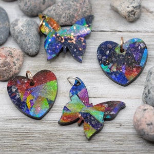 May include: Four colorful resin pendants in the shapes of hearts and butterflies. The pendants have a mosaic-like appearance with iridescent colors and glitter.