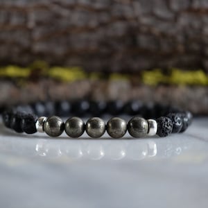 May include: A black lava rock and pyrite beaded bracelet. The bracelet has silver spacer beads.