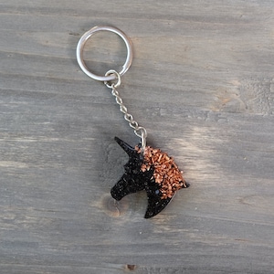 May include: Black and copper glitter unicorn keychain with a silver key ring and chain.