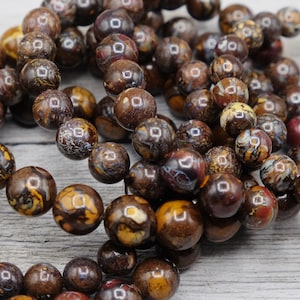 May include: A strand of brown, yellow, and white opal beads. The beads are round and have a smooth, polished finish.