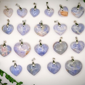 May include: A collection of 20 heart-shaped pendants made of blue lace agate. The pendants are all different shades of blue and have a natural, organic look. They are perfect for making jewelry or using in crafts.