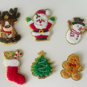 May include: Six festive Christmas fabric patches. The patches feature a reindeer, Santa Claus, a snowman, a stocking, a Christmas tree, and a gingerbread man. Each patch is trimmed with gold glitter.