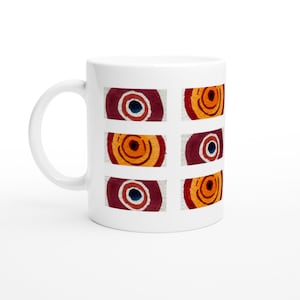 May include: A white ceramic mug featuring a repeating pattern of six rectangular blocks. Each block contains a hand-painted style circular motif in shades of deep burgundy, bright orange, and dark blue, arranged in a grid of two columns and three rows.