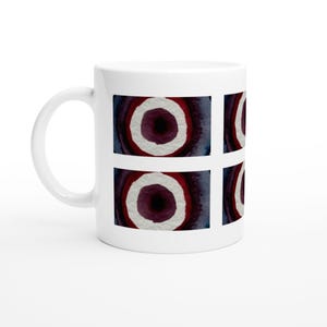 May include: A white ceramic mug featuring a repeating graphic pattern of four rectangular panels. Each panel displays a circular design with a dark purple centre, surrounded by concentric rings of white, deep red, and dark blue watercolour textures.