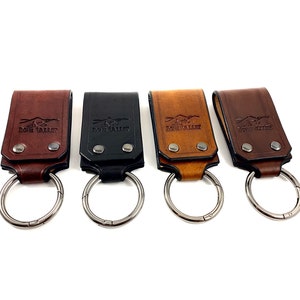 May include: Four leather keychains with a silver ring. Each keychain has a different color: brown, black, tan, and dark brown. The keychains have the words "Lone Valley" embossed on them.