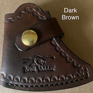 May include: Dark brown leather axe sheath with a snap closure and a decorative embossed design. The sheath has the text "Bone Valley" embossed on the front.