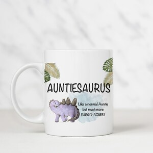 May include: White ceramic mug with a purple dinosaur illustration and the text "Auntiesaurus Like a normal Auntie but much more RAW-SOME!"