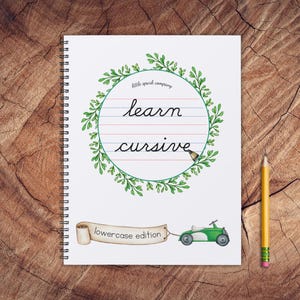 Peut inclure: Un cahier à spirales blanc avec une couronne de feuilles vertes autour d'un cercle qui dit "apprendre l'écriture cursive" en écriture cursive. Le cahier a une voiture jouet verte et blanche avec une bannière qui dit "édition minuscule".