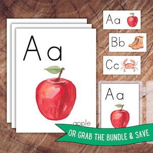 May include: A set of educational alphabet flashcards featuring watercolor illustrations. The cards display uppercase and lowercase letters alongside corresponding images of a red apple, brown boots, and a crab, with the text apple printed below.