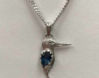 May include: A silver necklace with a pendant shaped like a bird with a blue gemstone in its chest.