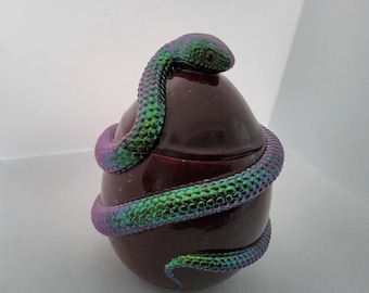 May include: A dark red, iridescent egg-shaped ceramic container with a green iridescent snake wrapped around it.
