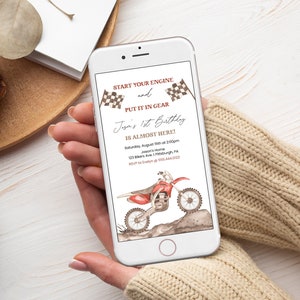May include: A digital invitation for a 1st birthday party with a motocross theme. The invitation features a red and black dirt bike, checkered flags, and the text "Start your engine and put it in gear. Jaya's 1st Birthday is almost here!" The invitation also includes the date, time, and location of the party.