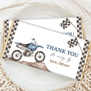 May include: A white chocolate bar wrapper with a blue and white dirt bike illustration, black and white chequered border, and the text "Thank You for racing by love, Oliver".