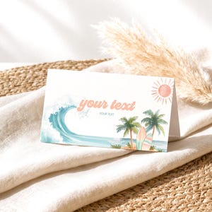 May include: A folded white card featuring a watercolor illustration of a blue ocean wave, green palm trees, surfboards, and a pink sun. The text "your text" is printed in a coral-colored script font, with the smaller text "YOUR TEXT" below it.