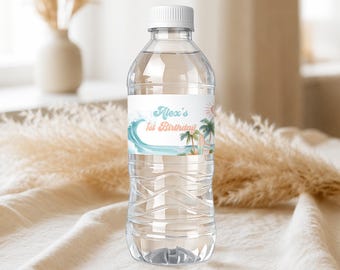Puede incluir: Una botella de agua de plástico transparente con una etiqueta blanca que muestra una ola azul, palmeras verdes y un sol. El texto en la etiqueta dice Alex's 1st Birthday en una fuente de color azul claro y naranja. La botella tiene tapa blanca.