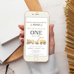 May include: A smartphone displays a construction-themed birthday invitation. The text reads "Stop the traffic and close the road! Daniel is turning ONE year old!" with illustrations of construction vehicles. The invitation includes date, time, and location details.
