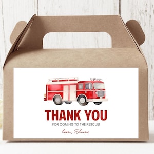 Könnte beinhalten: Eine braune Geschenkbox mit einem roten und weißen Feuerwehrauto. Die Botschaft auf der Box lautet "Vielen Dank, dass du zur Rettung gekommen bist! Liebe, Oliver".