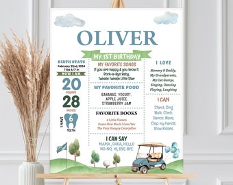 May include: A green and blue illustrated first birthday poster for a boy named Oliver. The poster includes his birth stats, favourite songs, foods, books, and things he can do. The poster also features a cartoon golf cart with balloons.