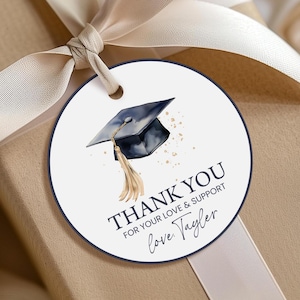 May include: Round white thank you tag with a black graduation cap, gold glitter, and the text "Thank You for your love & support love, Taylor".