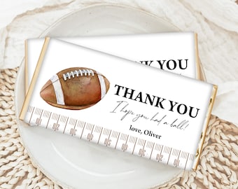 May include: Chocolate bar with a white wrapper featuring a watercolor football illustration. The text reads "THANK YOU I hope you had a ball! love, Oliver" with a football field yard marker design.