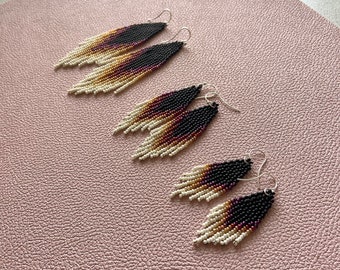 May include: Three pairs of beaded earrings in different lengths. The earrings are a gradient of white, tan, brown, and black beads.