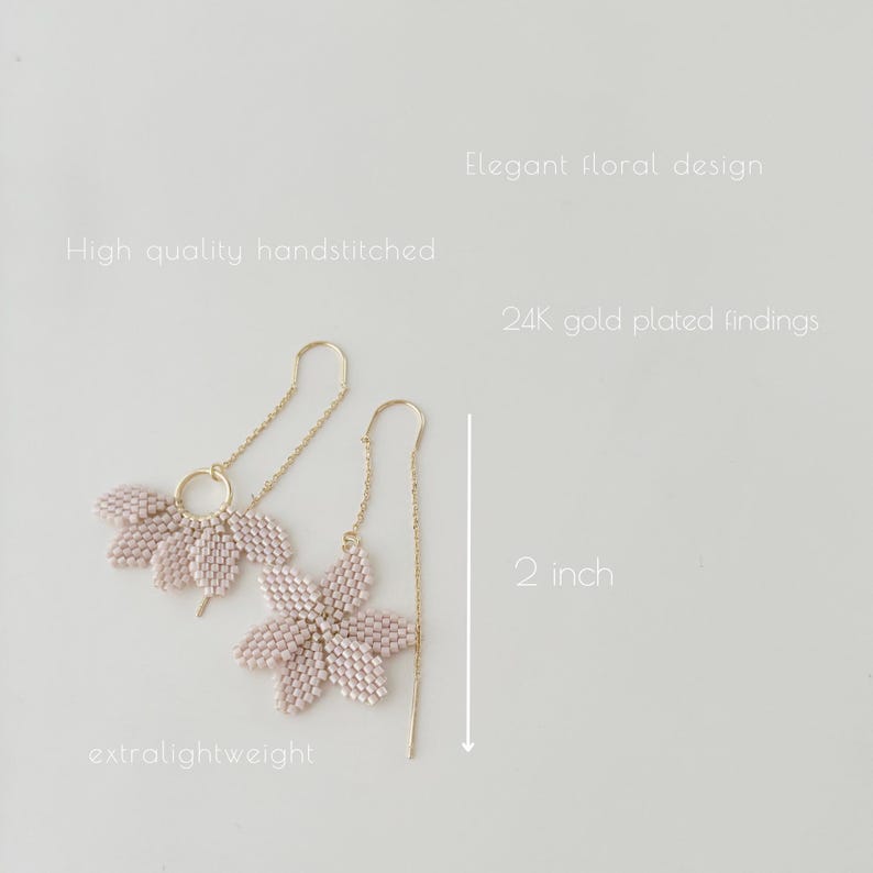 May include: A pair of delicate, blush pink flower dangle earrings with 24k gold plated findings. The earrings are 2 inches long and feature a delicate floral design.  The earrings are extra lightweight.