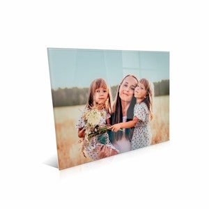May include: A rectangular glass wall art panel featuring a high-resolution photograph of an adult and two children standing in a golden field. The subjects are wearing light-colored polka dot clothing, and one child holds a bouquet of wildflowers.