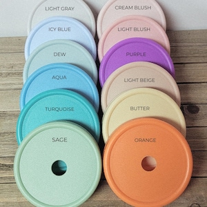 K&ouml;nnte beinhalten: Eine Sammlung von zehn kreisf&ouml;rmigen Deckeln, die in zwei Spalten angeordnet sind und mit LID COLORS beschriftet sind. Die Deckel sind in den Farben Hellgrau, Eisblau, Tau, Aqua, T&uuml;rkis, Salbei, Crem&eacute;-Blush, Hell-Blush, Lila, Hellbeige, Butter und Orange erh&auml;ltlich.