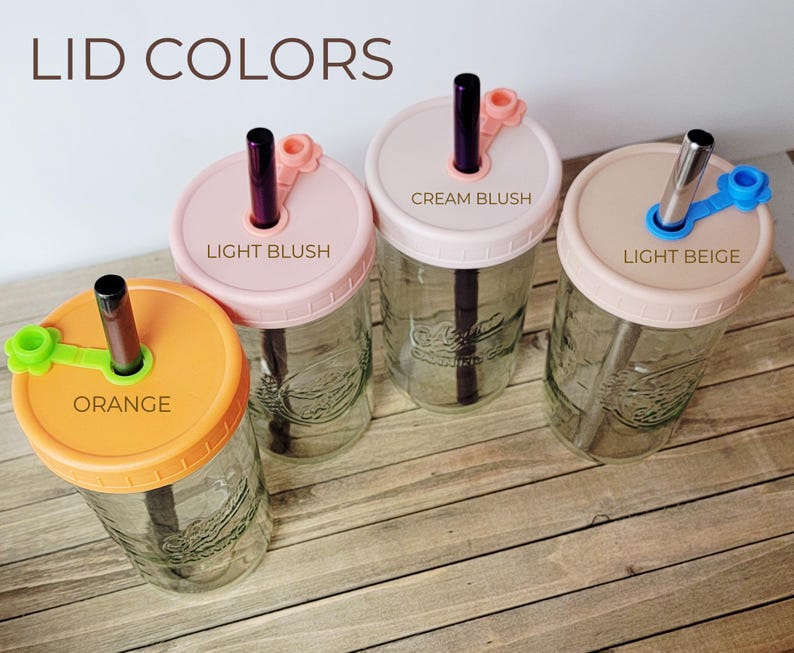 K&ouml;nnte beinhalten: Vier durchsichtige Einmachgl&auml;ser aus Glas mit Deckeln und Strohhalmen. Die Deckel sind mit Orange, Light Blush, Cream Blush und Light Beige beschriftet. Jeder Deckel hat einen passenden Silikonstopfen f&uuml;r den Strohhalm. Metallische Strohhalme.
