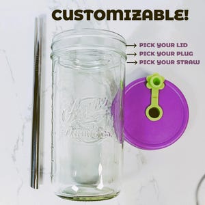 K&ouml;nnte beinhalten: Ein klares Einmachglas aus Glas mit einem Metallstrohhalm und einem violetten Deckel mit einem hellgr&uuml;nen blumenf&ouml;rmigen Verschluss. Der Text CUSTOMIZABLE! ist zu sehen, mit Pfeilen zu den Beschriftungen PICK YOUR LID, PICK YOUR PLUG und PICK YOUR STRAW.