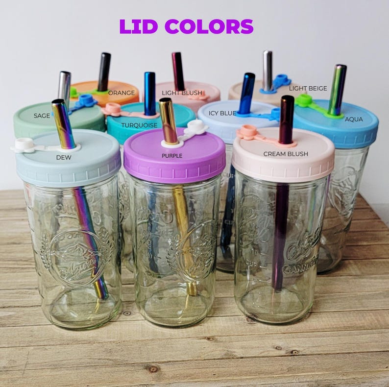 K&ouml;nnte beinhalten: Eine Sammlung von klaren Einmachgl&auml;sern aus Glas mit Schraubdeckeln in verschiedenen Farben wie Salbei, Tau, T&uuml;rkis, Lila, Crem&eacute;-Rouge, Eisblau, Hellbeige und Aqua. Jedes Glas ist mit einem passenden, wiederverwendbaren, irisierenden Metallstrohhalm ausgestattet.