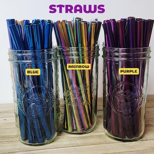 K&ouml;nnte beinhalten: Drei durchsichtige Gl&auml;ser gef&uuml;llt mit Metallstrohhalmen. Das linke Glas enth&auml;lt blaue Strohhalme mit der Aufschrift 'BLUE', das mittlere Glas regenbogenfarbene Strohhalme mit 'RAINBOW' und das rechte Glas violette Strohhalme mit 'PURPLE'. Oben steht der Text 'STRAWS'.