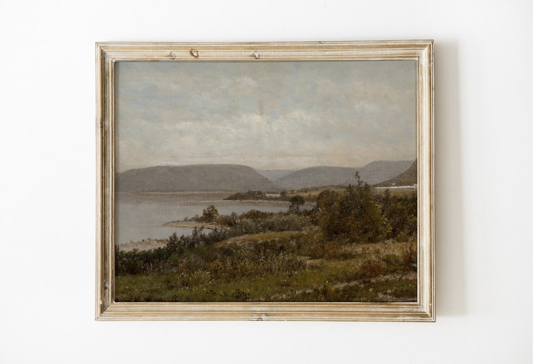 May include: A framed landscape painting depicting a lake with mountains in the background. The painting is done in muted tones of blue, green, and brown.