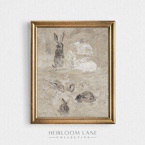 May include: A framed print of a vintage illustration featuring a group of rabbits in various poses. The rabbits are drawn in shades of gray and white on a textured beige background. The frame is gold.