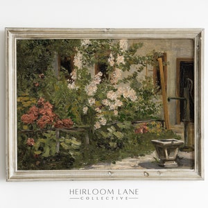 May include: A framed oil painting depicting a garden scene with a white building in the background. The garden is filled with lush greenery, pink flowers, and a stone well. The painting is framed in a light gray frame.