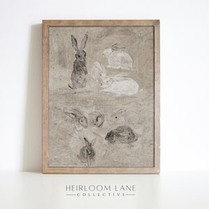 May include: A framed print of a vintage illustration featuring a group of rabbits in various poses. The rabbits are drawn in shades of gray and white on a beige background. The frame is a simple wooden frame with a light brown finish.