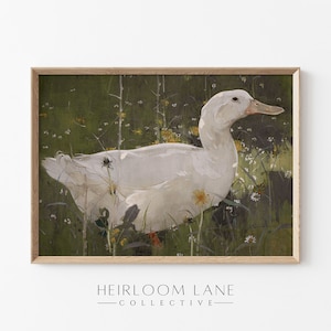 K&ouml;nnte beinhalten: Eine wei&szlig;e Ente mit gelbem Schnabel steht in einem Feld aus gr&uuml;nem Gras und gelben Blumen. Die Ente ist in einem hellbraunen Holzrahmen gerahmt.