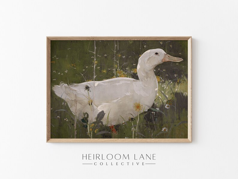 K&ouml;nnte beinhalten: Eine wei&szlig;e Ente mit gelbem Schnabel steht in einem Feld aus gr&uuml;nem Gras und gelben Blumen. Die Ente ist in einem hellbraunen Holzrahmen gerahmt.