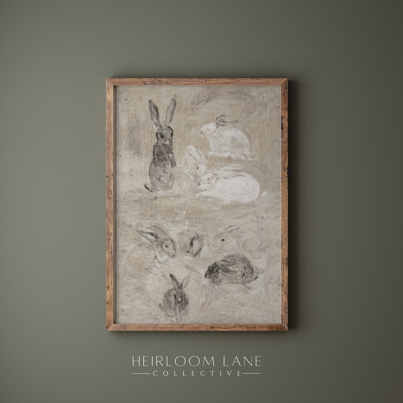 May include: A framed print of a black and white drawing of rabbits. The drawing is on a beige background and the frame is a light brown wood.