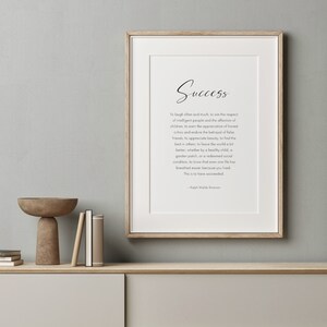 Puede incluir: Impresi&oacute;n enmarcada con la palabra "Success" en escritura elegante. La impresi&oacute;n presenta una cita de Ralph Waldo Emerson sobre un fondo blanco. El marco es de color madera clara, y la impresi&oacute;n se muestra en una estanter&iacute;a de tonos neutros.