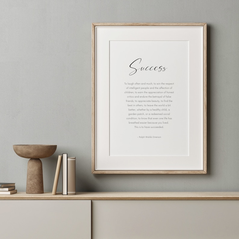 Puede incluir: Impresi&oacute;n enmarcada con la palabra "Success" en escritura elegante. La impresi&oacute;n presenta una cita de Ralph Waldo Emerson sobre un fondo blanco. El marco es de color madera clara, y la impresi&oacute;n se muestra en una estanter&iacute;a de tonos neutros.