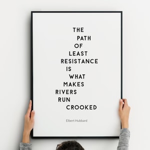 May include: Black and white framed print with a quote by Elbert Hubbard: "The path of least resistance is what makes rivers run crooked."